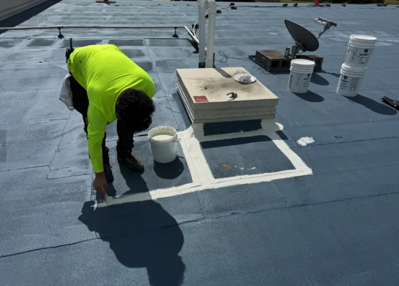 Technician sealing flashing around a rooftop curb.