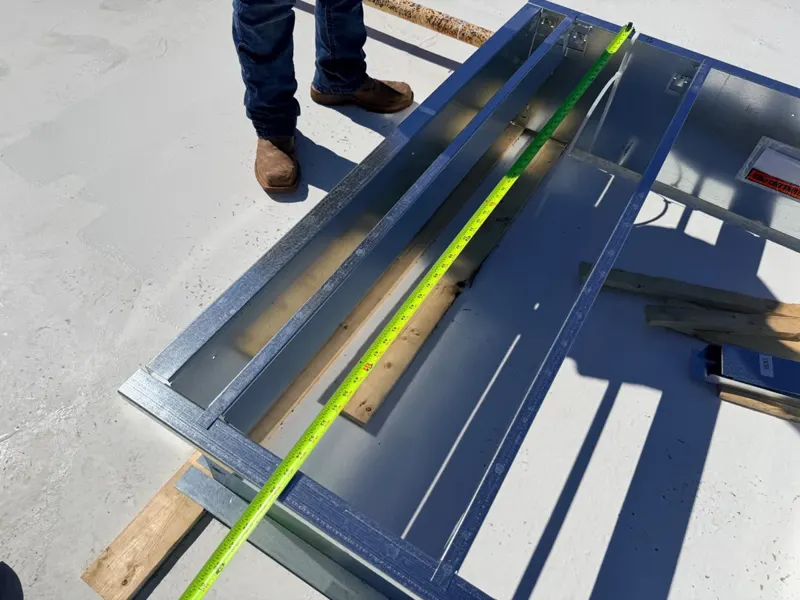 Technician fitting metal flashing on a commercial roof.