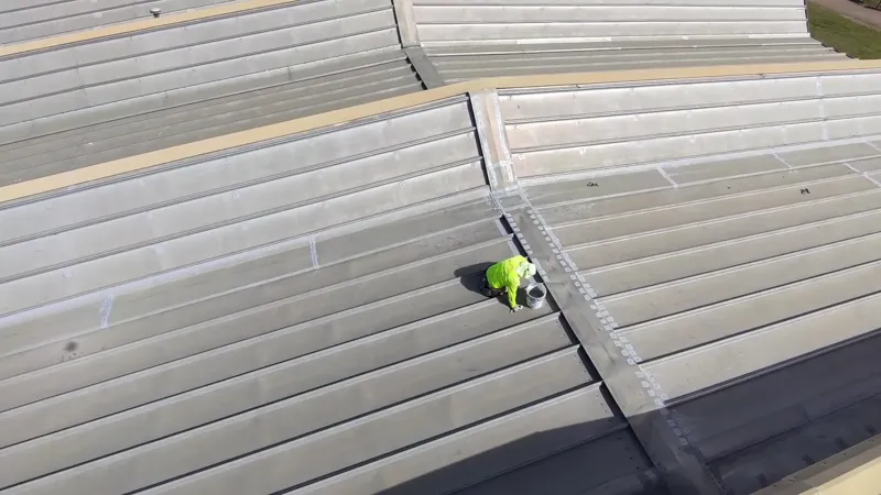 Technician sealing seams on a commercial metal roof.